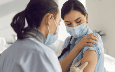 A woman administering a vaccine to a female patient's right arm.