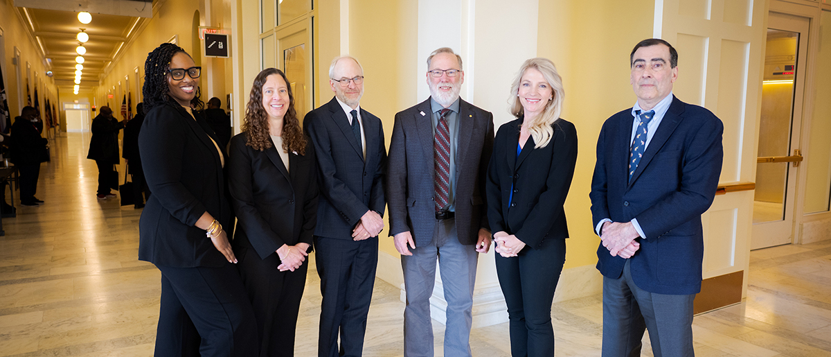 Speakers for the AAI Congressional Briefing stand in the halls of the House Office Building.