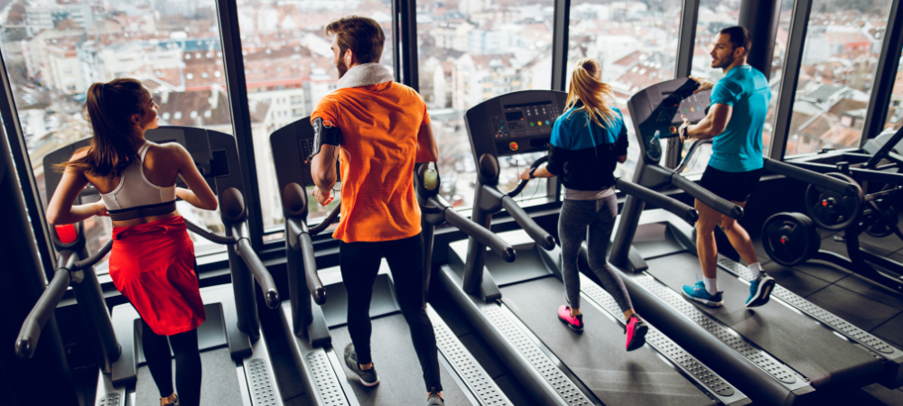 Four people running HIIT workouts beside each other on treadmills