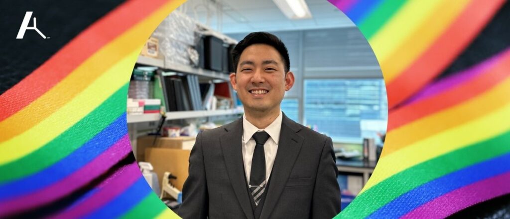 Photo of Stephen T. Yeung in his lab, surrounded by a Pride flag ribbon image.
